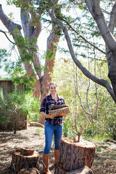 Woman holding pile of wood outdoors