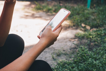 Closeup of young lady's hand holding a soft pink rubber covered mobile phone. Selective focus. Copy space.