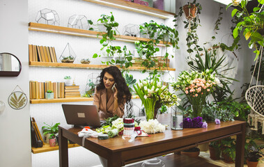 Attractive young woman florist is working in a flower shop.