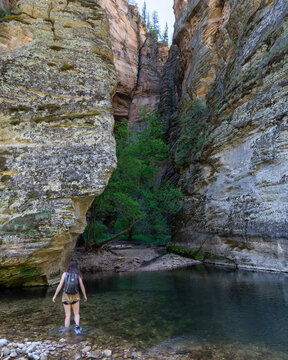 Woman crossing water on a hike in a slot canyon.