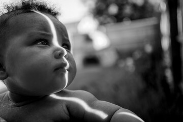 beautiful baby with brown eyes looking out with ray of light on her face covered with her muslin #2...