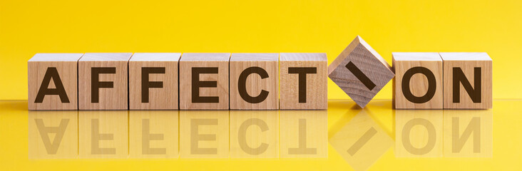 Word AFFECTION is made of wooden building blocks lying on the table and on a light yellow background. Concept