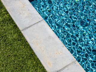 Poolside with green grass and vibrant color water