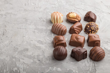 Different chocolate candies on a gray concrete background. side view, copy space.