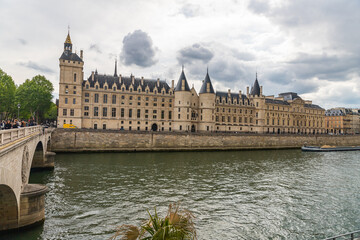 Fototapeta na wymiar View of medieval palace Conciergerie, Seine river with barge and Neuf bridge in Paris, France