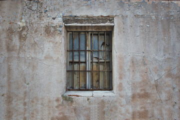 old window with broken glass on an old facadeold window with broken glass and grille on an old abandoned building