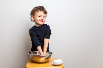 the boy is soaping his hands. Hygiene rules and good habits. The child washes his hands with a dense soap bar on a white studio background. isolated