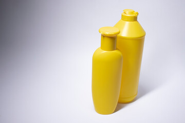 Composition of two yellow shampoo bottles with no label. body care and beauty concept. Copy space. Isolated. High quality photo