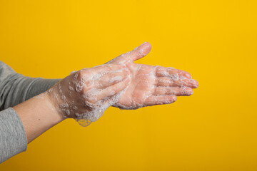Fototapeta premium washable hands close-up on a yellow studio background. Proper hand washing as a prevention of viruses .