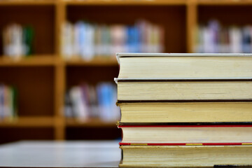 Stack of books and blurred bookshelf in the library, education background, back to school concept.