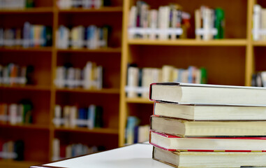 Stack of books and blurred bookshelf in the library, education background, back to school concept.