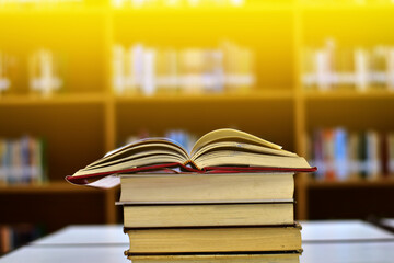 Open Book on wood table and blurred bookshelf in the library, education background, back to school concept.
