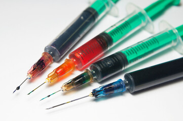 Ink of different colors in syringes for refilling cartridges from inkjet printers. Selective focus.