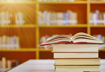 Open Book on wood table and blurred bookshelf in the library, education background, back to school...