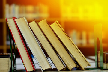 Stack of books and blurred bookshelf in the library, education background, back to school concept.