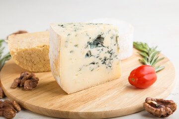 Blue cheese and various types of cheese with rosemary and tomatoes on wooden board on a white background . Side view, selective focus.