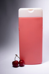 big pink shampoo bottle with white neck and no label near cherry. body care and beauty concept. Copy space. High quality photo