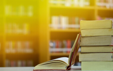 Open Book on wood table and blurred bookshelf in the library, education background, back to school concept.