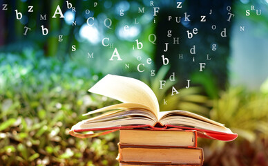 Open book on the table and English alphabet Floating above the book in the library and blur nature background.