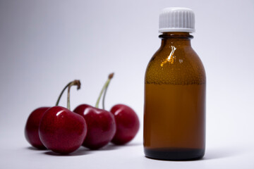 little liquid bottle with no label near cherry. body care and beauty concept. Copy space. High quality photo