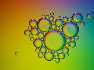 Closeup yellow oil bubbles with colorful background and blurred droplets ,macro image ,sweet pastel color ,rainbow and colorful balloons background, abstract background