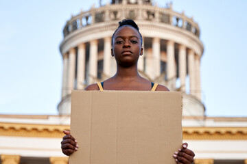 Young african woman activist stand outdoor hold empty blank sign protesting on street. Black female...