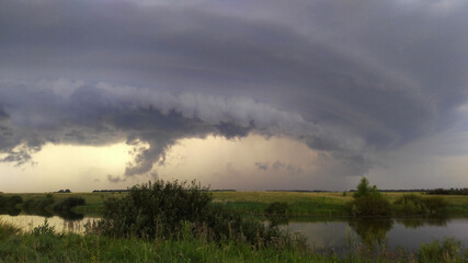 Fototapeta premium thunderstorm over the river. low clouds before the rain. a thunderstorm and a hurricane are approaching the pond. tornado. the sky is in clouds. bad weather.