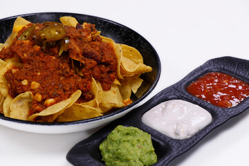 mexican nachos chips with chili beef, avocado, sour cream and tomato salsa
