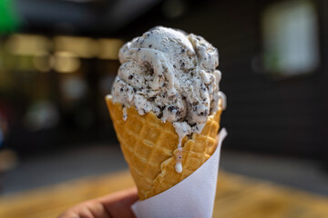 hand holding cookies and cream icea cream on a hot summer day