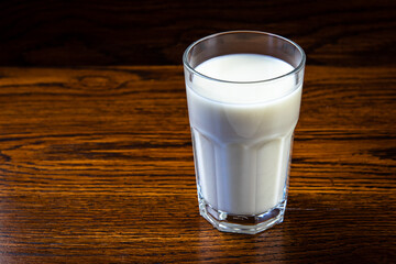 glass of milk on old wooden table dark background