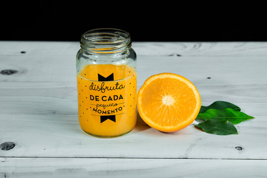 Jugo De Naranja Sobre Jarro De Vidrio Con Hojas Verdes