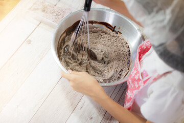 Fototapeta premium A girl making chocolate brownies. Preparation for maxing chocolate cake or homemade brownie cake.