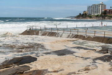 Ocean storm aftermath: A mass of thick foam covered the rocks near rock pool following extreme...