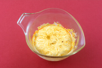Roasted red pepper pesto and sour cream sauce in glass measuring cup on red background