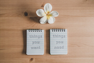 notepads with titles Things you need vs things you want side by side on desk ready for meditation