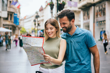 Happy tourists couple looking at a map