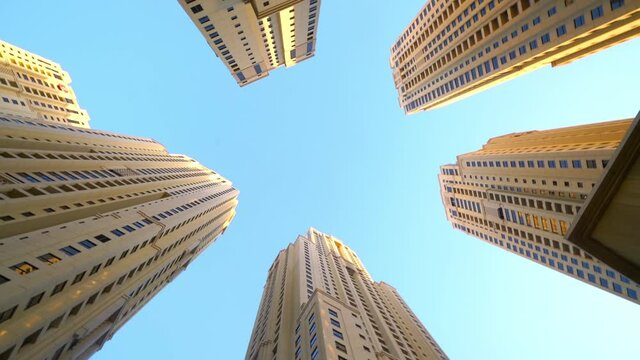 High Rise Buildings With Blue Sky - Waterfront Community Of Jumeirah Beach Residences In Dubai Marina in Dubai, United Arab Emirates. -low angle rotation