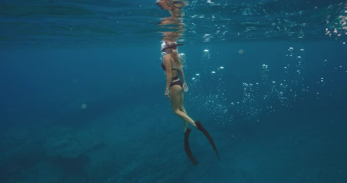 Beautiful woman swimming underwater free diving in deep blue ocean, outdoor adventure lifestyle