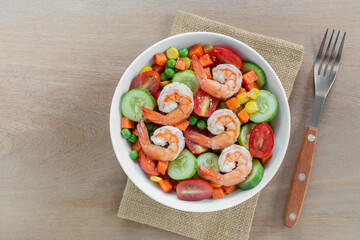 top view of shrimps salad with sesame soy sauce in a ceramic bowl on wooden table. homemade style food concept.