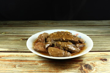 Pile of fried pork liver seasoning with traditional soy sauce and fresh chopped garlic on the plate. Famous menu in Asia restaurant. 