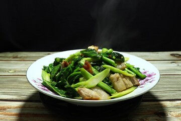 Fresh Chinese kale with roasted crispy pork and seasoning with pepper and fish sauce on the plate. Famous ancient food in Asia restaurant. Appetizer menu and side dish with porridge rice.  