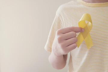 Hands holding yellow gold ribbon, Sarcoma Awareness, Bone cancer, childhood cancer awareness, September yellow, World Suicide Prevention Day concept