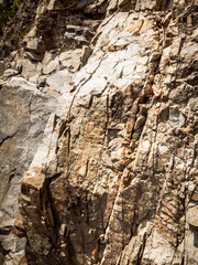 Natural background. Closeup edged shabby cliff cracks. Gray-brown stone rock texture of mountains. Vintage and faded matt style colour in tinted photo. Concept of geolog, mountaineering or hard work