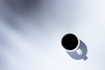 White cup with a coffee on a light background. Top view, flat lay