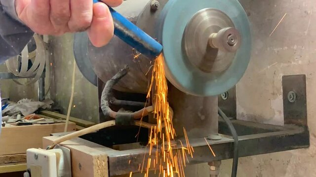 Grinding metal rod on a metal grinding machine in super slow motion. Sparks flying.