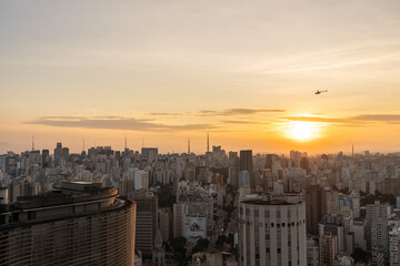 por do sol na cidade de Sao Paulo com seus prédios icônicos e um helicóptero ao fundo