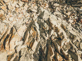 Natural background. Closeup edged shabby cliff cracks. Gray-brown stone rock texture of mountains. Vintage and faded matt style colour in tinted photo. Concept of geolog, mountaineering or hard work