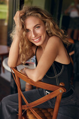 Woman Portrait. Beautiful Curly Blonde Model Resting On Chair In Cafe. Sexy Female Healthy Natural Look. Relaxation In Comfortable Restaurant.