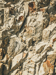 Natural background. Closeup edged shabby cliff cracks. Gray-brown stone rock texture of mountains. Vintage and faded matt style colour in tinted photo. Concept of geolog, mountaineering or hard work