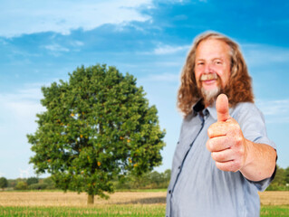 Fototapeta premium Older man shows thumbs up on field
